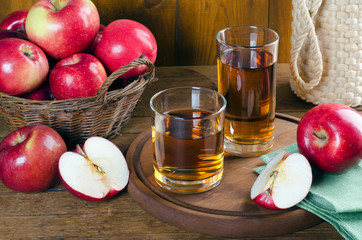 Apple juice in glasses and red apples.