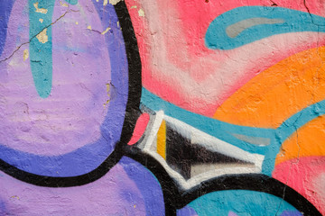 Colorful Graffiti texture on wall as background. Close up with detail Colorful  red, orange, violet, purple sprayed graffiti on aged cracked brick wall with drips, smears and peeling paint