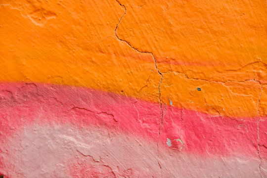 Colorful Graffiti texture on wall as background. Closeup with detail Colorful  red orange and sprayed graffiti on aged cracked brick wall with drips, smears and peeling paint