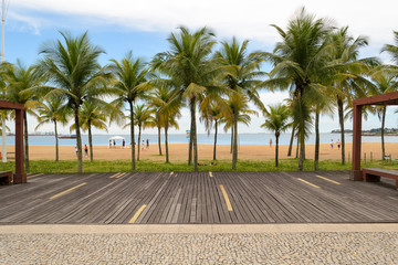 The seafront of the nice city of Vitoria, Espirito Santo in Brazil. A wooden deck and some palm trees just in front of the beach