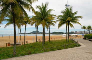 Fototapeta na wymiar The lovely seafront and main beach of the city of Vitoria in the Espirito Santo state in Brazil. Some characteristic palm trees in the foreground