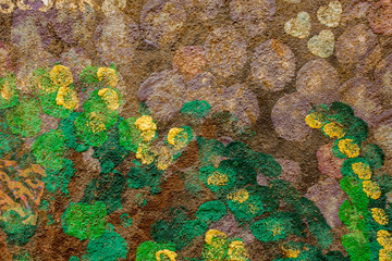 purple green and yellow spots on the brown concrete wall. rough surface texture