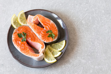 fresh fish. fresh salmon steaks with lemon, spices and salt in a dark plate