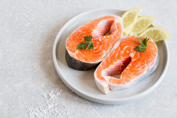 fresh fish. fresh salmon steaks with lemon, spices and salt in a light plate
