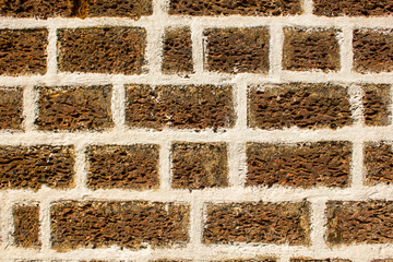 brown gray wall of porous volcanic stone blocks with white cement. rough surface texture