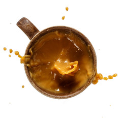 Cup of coffee isolated on white. Coffee splash. Top view, close-up.