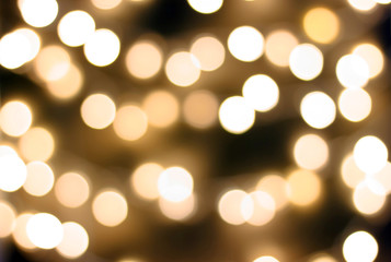 Bokeh abstract texture. Defocused dark background with blurred bright yellow and golden lights.