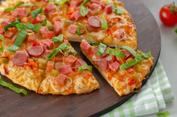 Slices of pizza with greens,sausage and salami, cherry tomatoes are on the table.