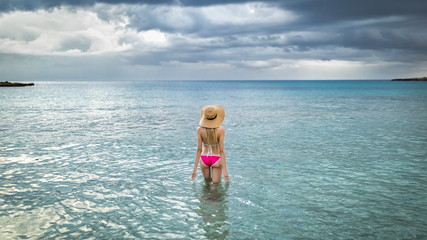 Tourist woman in straw hats for summer in a rose swimsuit Hawaii, Phuket, Maui. Space for text