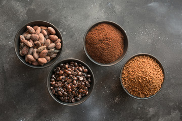 Concept of cocoa and coffee beans in bowls on dark.