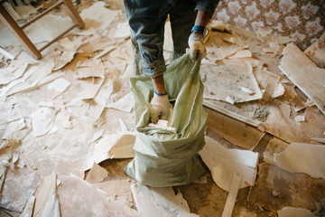Worker cleans the trash in the apartment in the bag