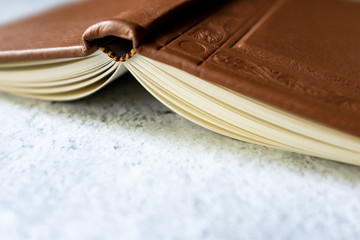 Brown leather vintage notebook blank pages open upside down on bright white and gray concrete color...