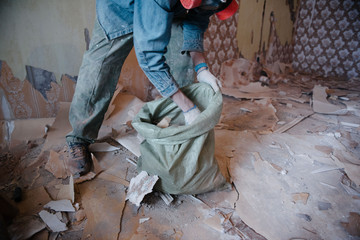 Worker cleans the trash in the apartment in the bag