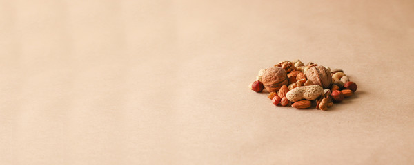 Hazelnuts, cashews, peanuts, walnuts, almonds, seeds lie on a beige background. 