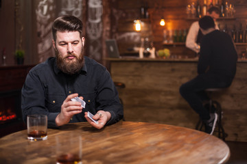 Handsome bearded man lost on his thoughts next to a glass of whiskey