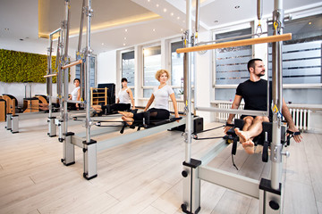 Fototapeta na wymiar Slim,sporty and attractive group of people doing Pilates exercise at the gym using Pilates equipment,healthy lifestyle concept