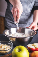 Making dough for apple pie by female hands. The  cook mixes ingredients for apple pie.