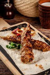 The concept of Georgian cuisine. Juicy lula kebab made from meat and spices. Serving dishes in a restaurant on a pita, on a wooden board. copy space, background image