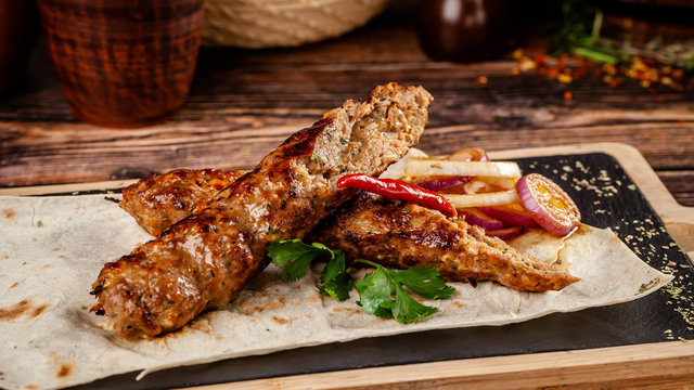 The concept of Georgian cuisine. Juicy lula kebab made from meat and spices. Serving dishes in a restaurant on a pita, on a wooden board. copy space, background image