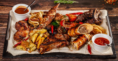 Concept of Georgian cuisine. Large meat board with shashlik, roasted meat, french fries, roast lamb and sauce. Serving dishes in a restaurant on a pita. Top view, copy space