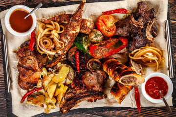 Concept of Georgian cuisine. Large meat board with shashlik, roasted meat, french fries, roast lamb and sauce. Serving dishes in a restaurant on a pita. Top view, copy space