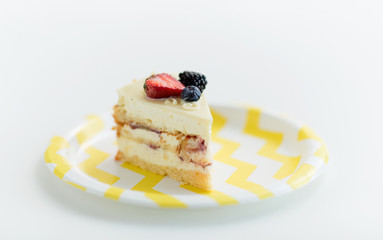 party food, junk-food and sweets concept - piece of delicious berry layer cake on disposable plate over white background