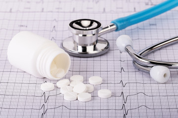 White pills and stethoscope on a cardiogram.Сoncept verification, care of health heart,diagnosis and treatment of cardiovascular diseases.