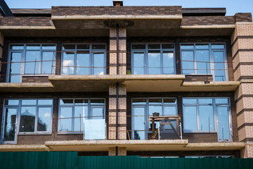 Balconies with trestle tables of unfinished modern brick building under construction