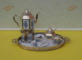 English teacup, saucer, silver-plated teapot on a silver stove, cream jug, sugar bowl and sugar...