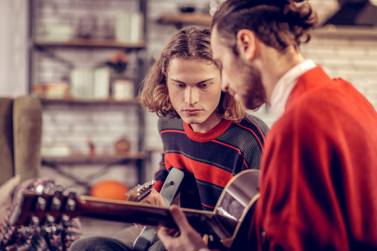 Handsome blonde-haired man playing guitar with brother