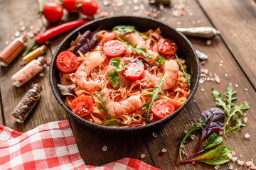 Tasty pasta with shrimp and tomato on a frying pan