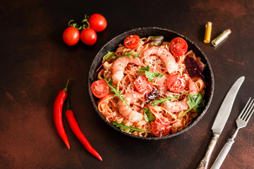 Tasty pasta with shrimp and tomato on a frying pan
