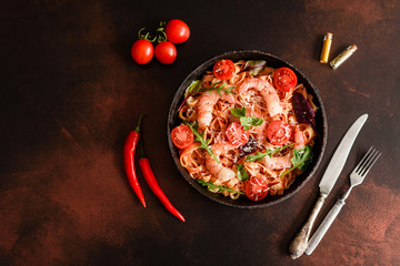 Tasty pasta with shrimp and tomato on a frying pan