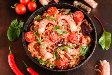 Tasty pasta with shrimp and tomato on a frying pan