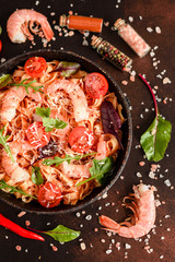 Tasty pasta with shrimp and tomato on a frying pan