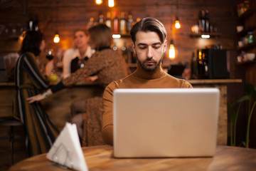 Handsome businessman working on his laptop in a vintage coffee shop