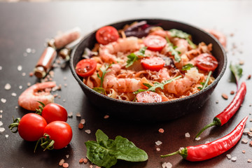 Tasty pasta with shrimp and tomato on a frying pan