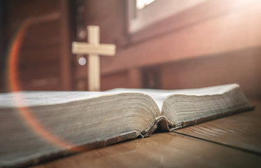Close up of old holy bible with christian cross standing at background. christian concept.