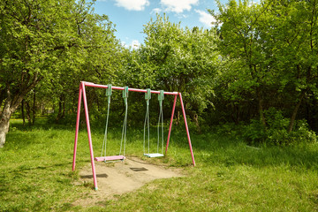 children's empty swing in the park on background of trees
