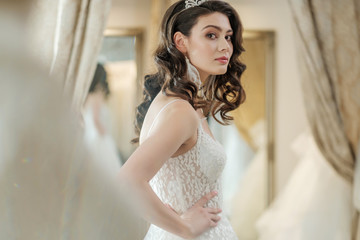 Naklejka premium Beautifu bride choosing wedding dress in a wedding salon