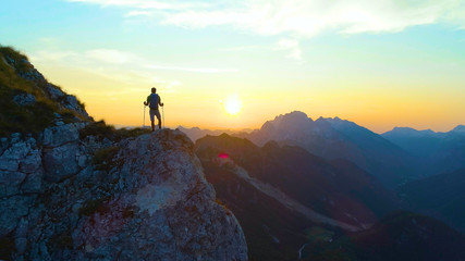 SILHOUETTE: Unrecognizable male tourist hiking in the Alps observing the sunset.