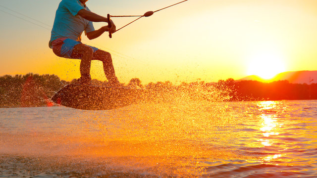 CLOSE UP: Cool wakeboarder does a 180 ollie while speeding across the lake.