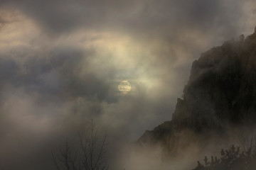 The sun in the fog among the clouds in the mountains