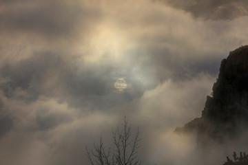 The sun in the fog clouds in the mountains