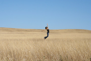 Adult girl running away through field. Beautiful warm summer day