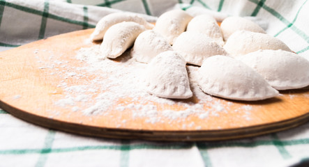 Raw dumplings sprinkled with flour on a kitchen board and a striped towel
