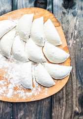 Raw dumplings sprinkled with flour on a kitchen board