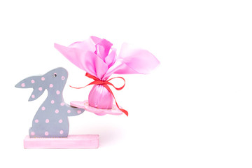 Wooden rabbit with gift pink Easter egg on a white background, Easter gift concept, copy space, isolated, surprise