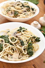 two plates of spaghetti with spinach and mushrooms
