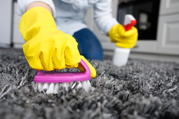 Girl cleans the carpet with a brush